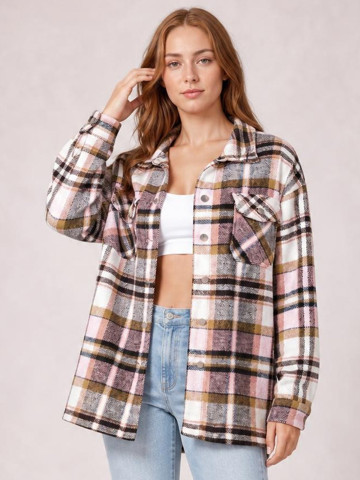 Model wearing a pink, beige, and black plaid button-front shirt jacket with a collared neckline, long dropped-shoulder sleeves, and breast pockets.
