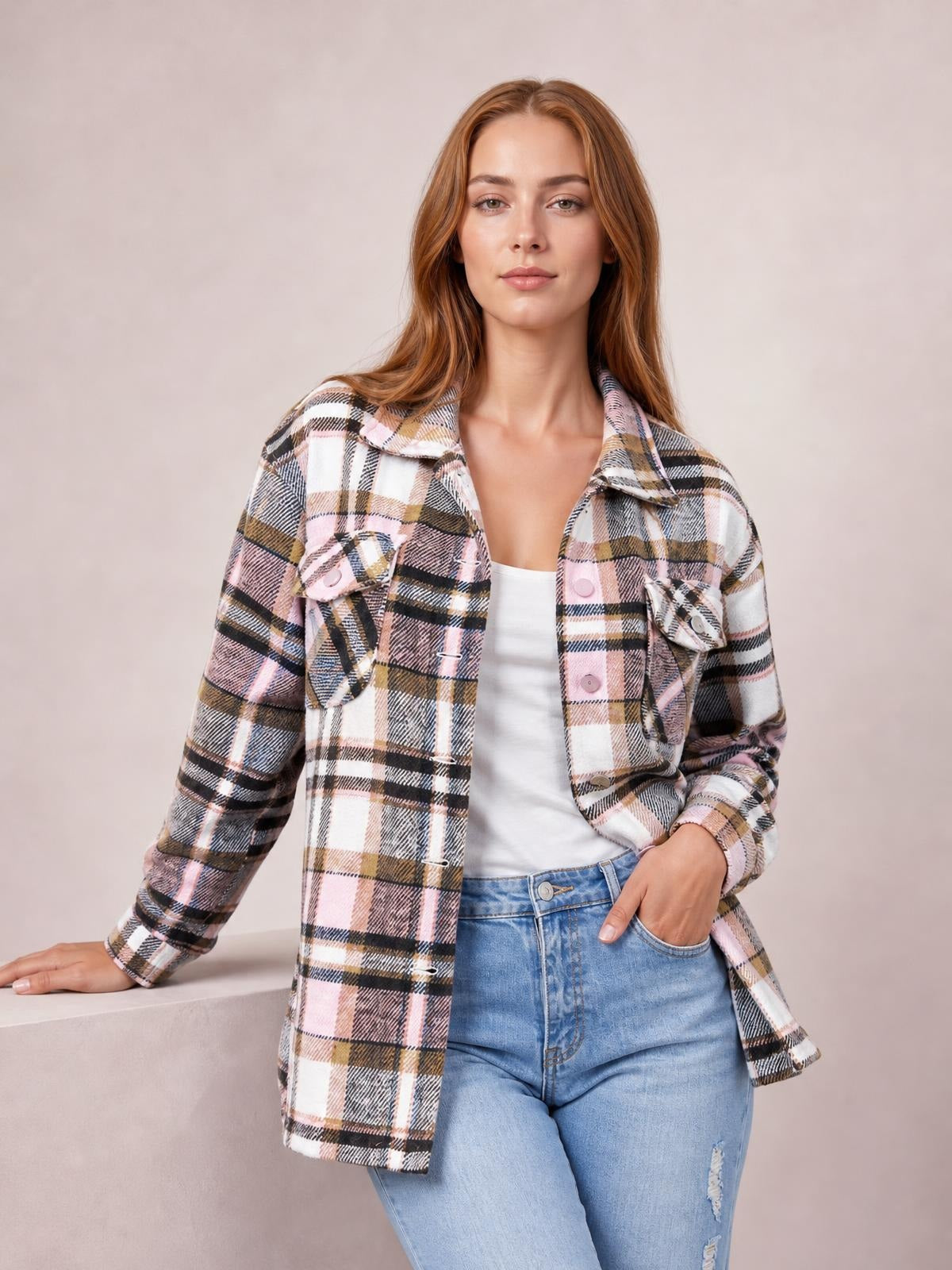 Model poses in a pink, white, black, and tan plaid button-front shirt jacket with a collared neckline, long dropped-shoulder sleeves, and two breast pockets.
