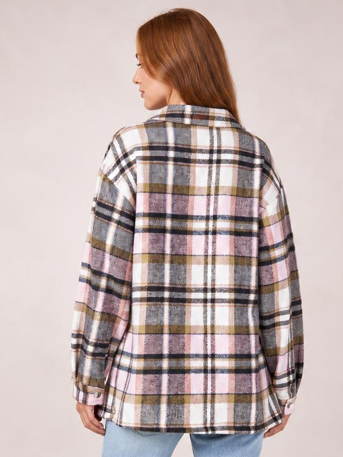 Model shown from the back in a relaxed pose wearing a pink, white, black, and olive plaid button-front shirt jacket with a collared neckline, long dropped sleeves, and an easy fit.