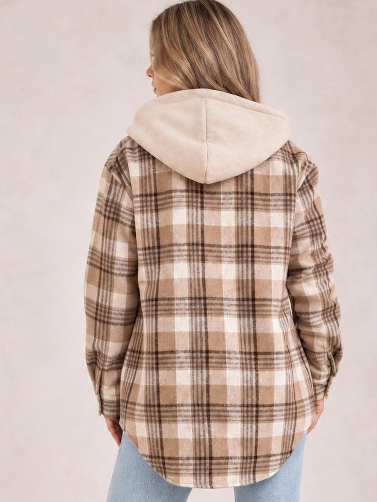 Model seen from behind wears a beige and brown plaid button-up jacket with a removable hood, long sleeves, relaxed fit, and curved hem.