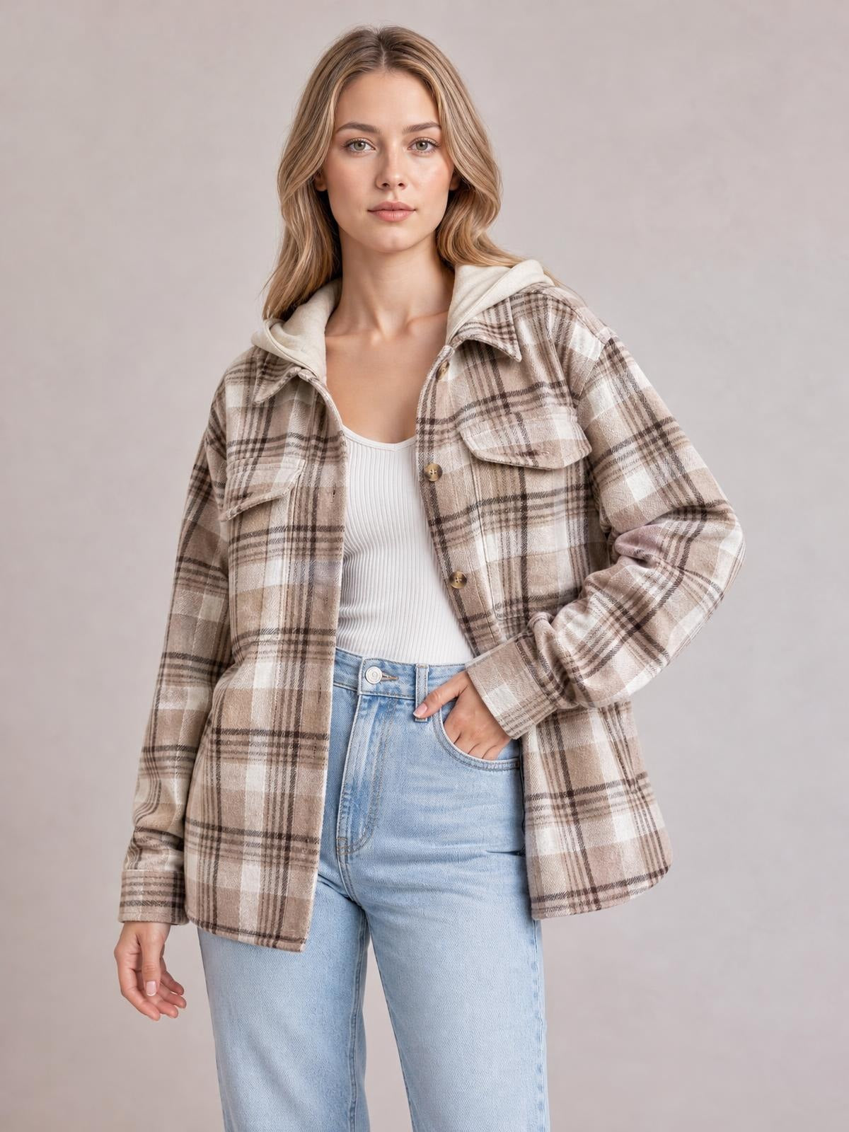 Model poses in a beige and brown plaid button-up jacket with a hood, flap chest pockets, long sleeves, and a relaxed straight silhouette.