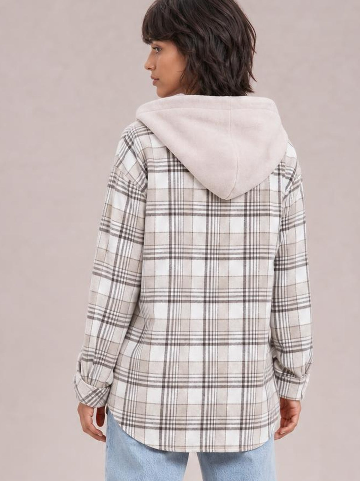 Model shown from the back wearing a relaxed white and gray plaid button-up jacket with long sleeves, curved hem, and a removable hood.