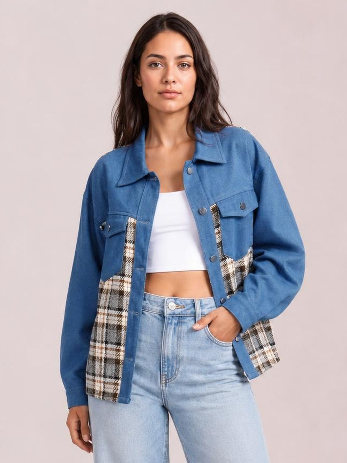 Model wears a blue long-sleeve denim jacket with plaid panels, button front, flap pockets, pointed collar, and a relaxed silhouette, posed with one hand in her jeans pocket.