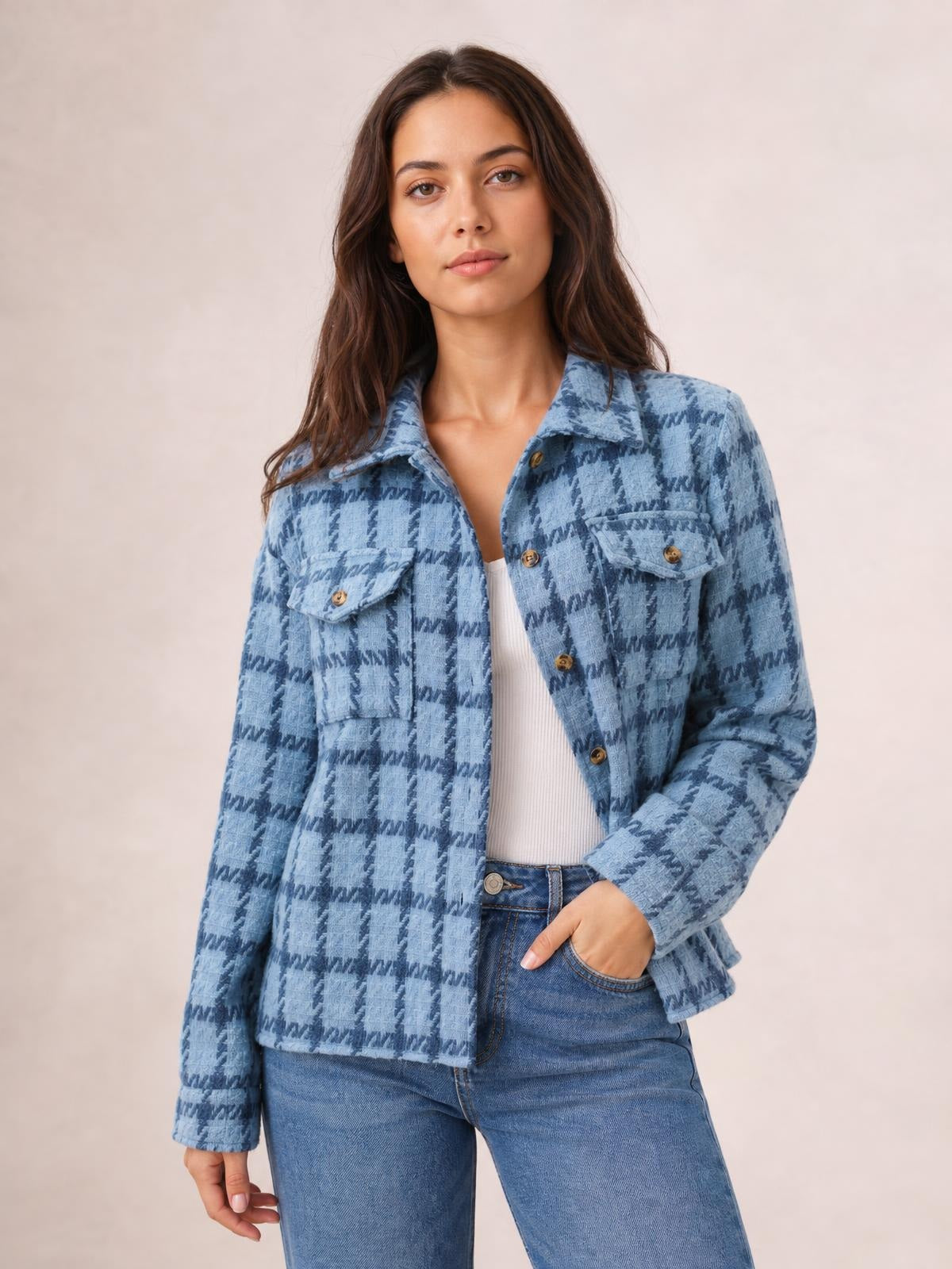 Model poses in a blue plaid button-up long sleeve jacket with a collared neckline, front buttons, flap pockets, and a relaxed cropped silhouette.