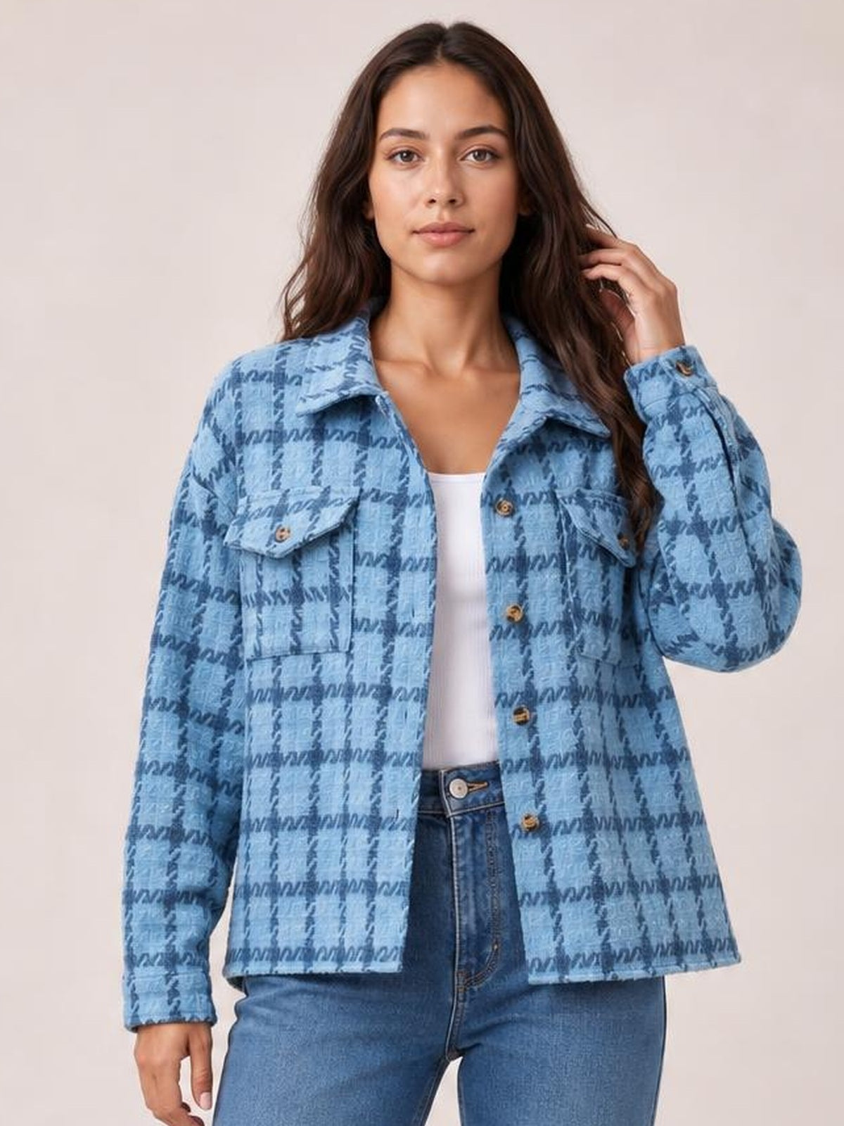 Model poses in a blue plaid button-up long sleeve jacket with a collared neckline, chest pockets, front buttons, and a relaxed silhouette.