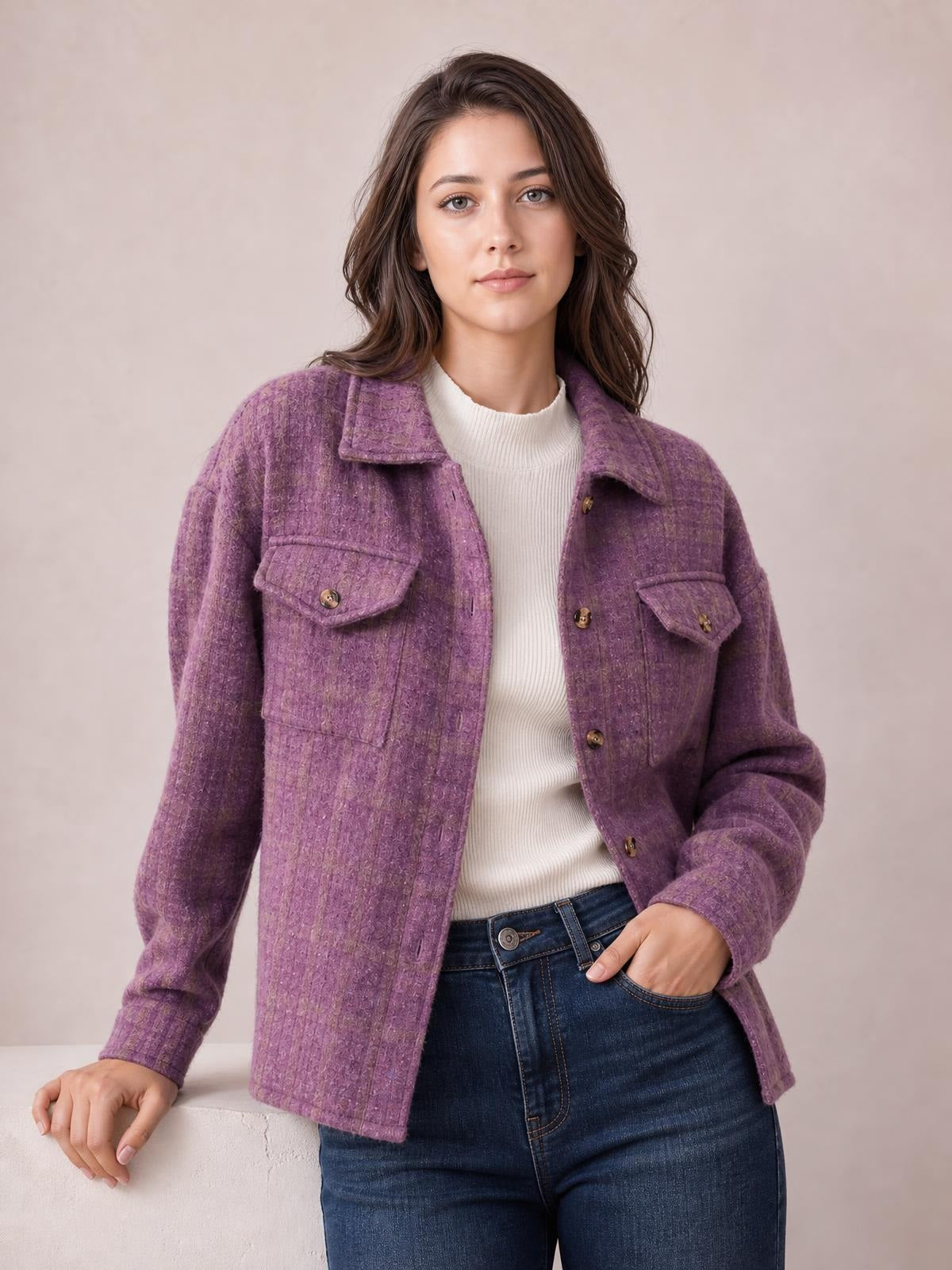 A woman wears a purple button-up long-sleeve jacket with a collared neckline, relaxed silhouette, front flap pockets, and visible brown buttons.