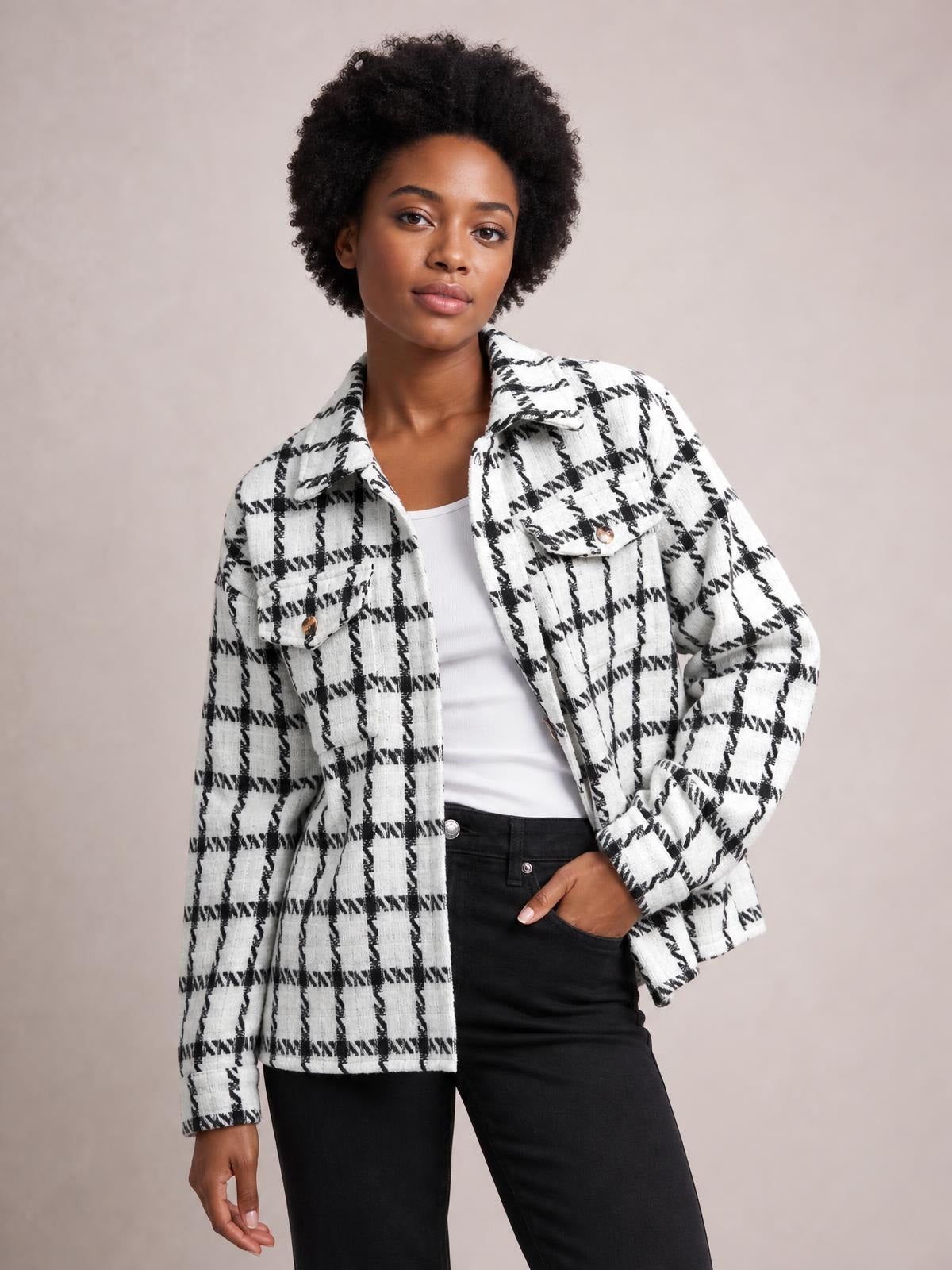 Model poses in a black-and-white plaid button-up long sleeve jacket with a collared neckline, front buttons, chest pockets, and a relaxed silhouette.