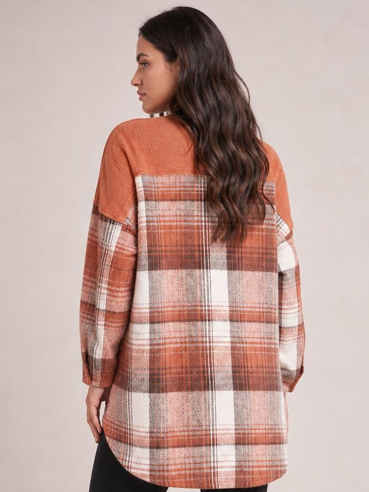Model shown from behind wearing a rust, cream, and brown plaid button-up long sleeve jacket with a relaxed oversized silhouette and curved hem.