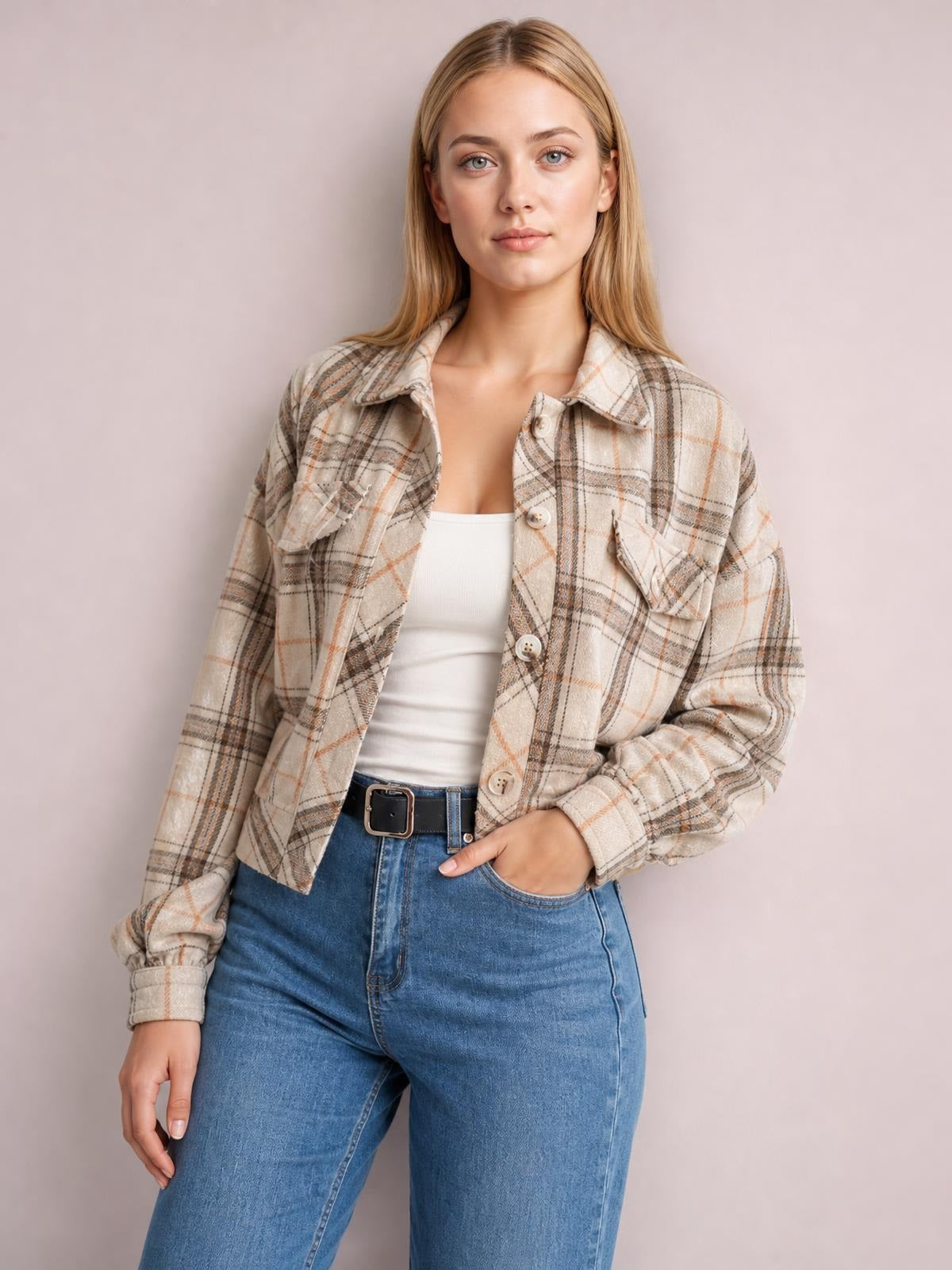 Model wears a beige plaid button-up long-sleeve jacket with a collared neckline, patch pockets, relaxed silhouette, and one hand tucked into her jeans pocket.