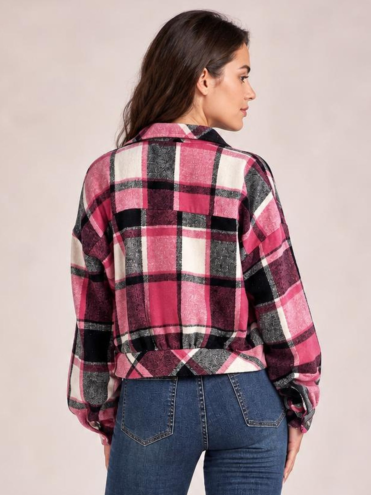 Woman looks over her shoulder wearing a cropped pink, black, white, and gray plaid button-up jacket with a collar, long sleeves, and relaxed silhouette.