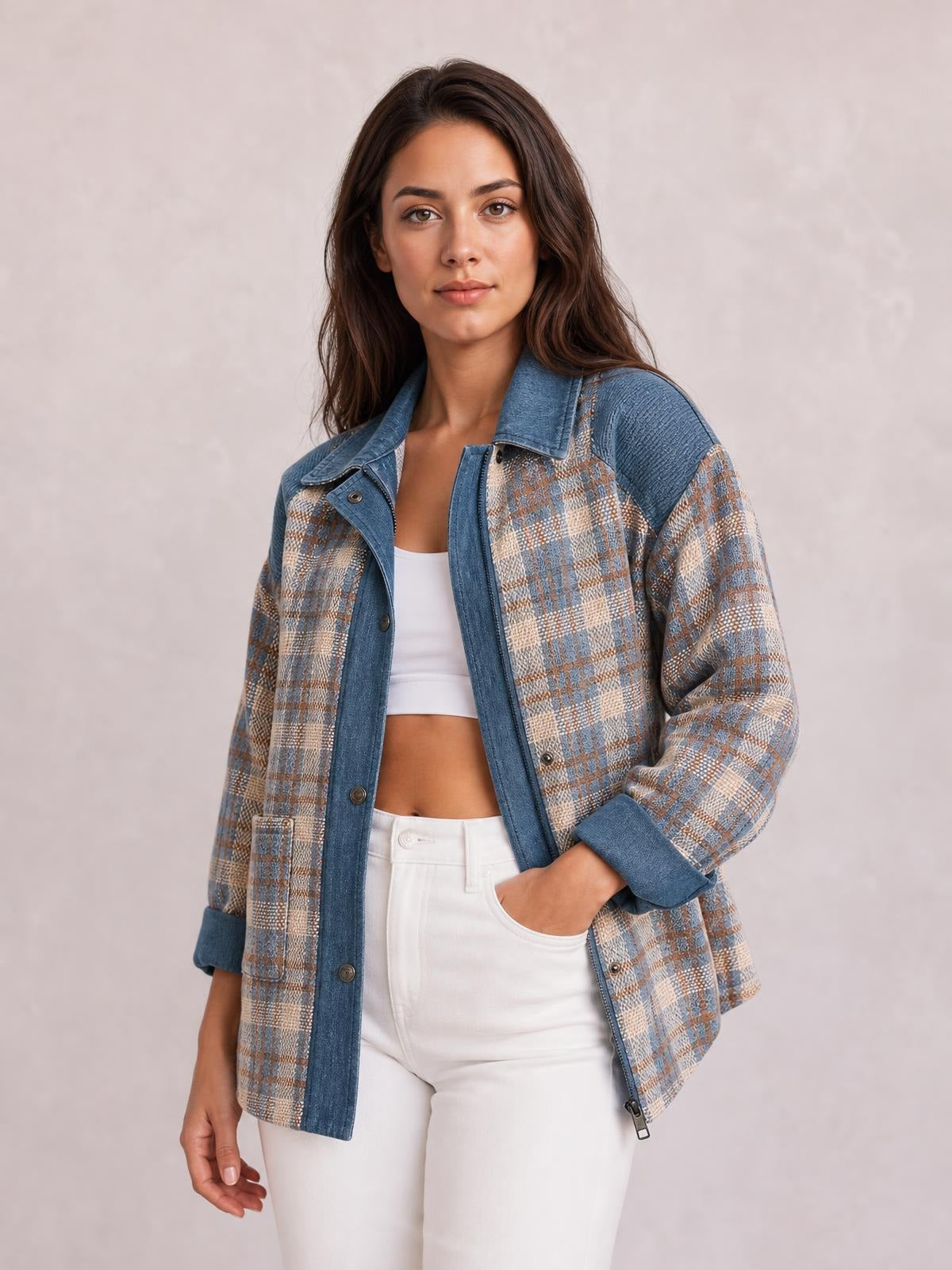 A model poses in a blue, tan, and cream plaid corduroy patchwork jacket with a collared zip-up front, snap buttons, and rolled cuffs.