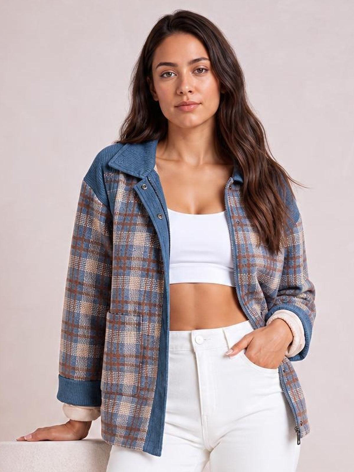 A woman poses in a blue and brown plaid patchwork corduroy jacket with a collared zip-up snap-button front, ribbed trim, relaxed silhouette, and pockets.