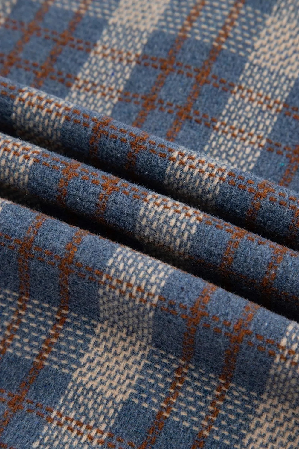 Close-up of the jacket’s blue plaid fabric with cream and brown intersecting stripes and a soft, textured finish.