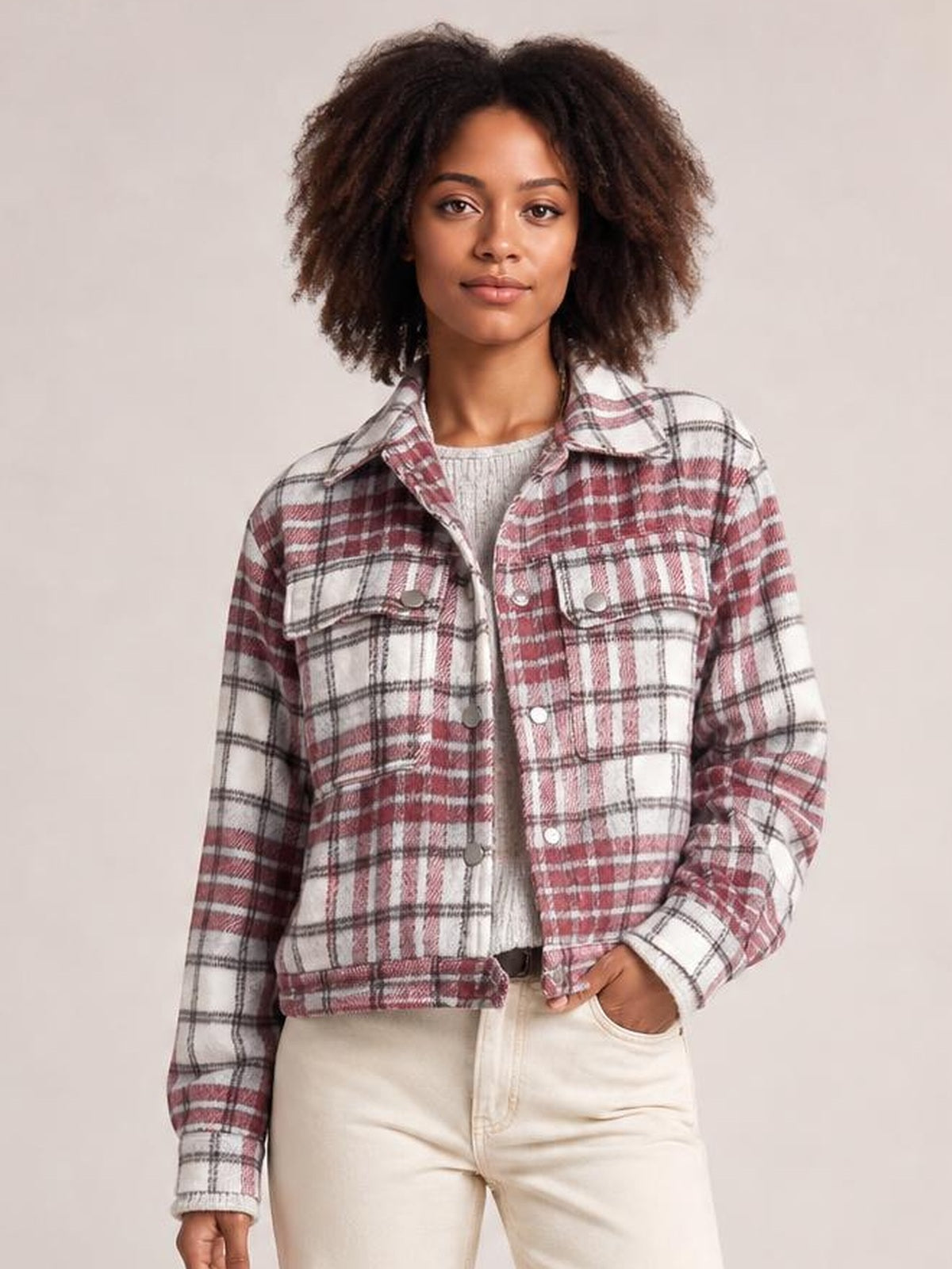 Model wearing a burgundy, white, and black plaid flannel shift jacket with a collar, metal buttons, chest pockets, and long sleeves.