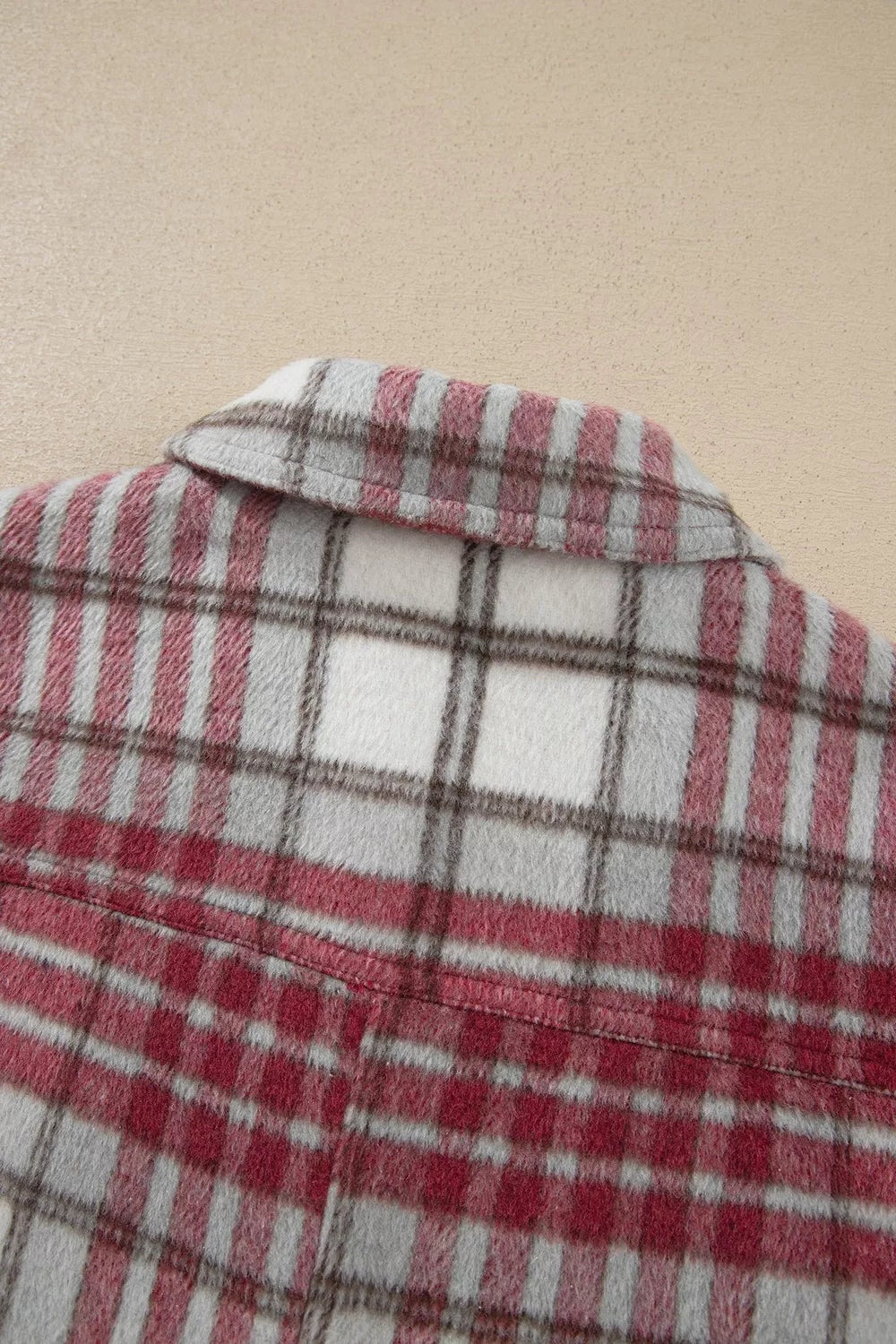 Close-up of a vintage plaid flannel jacket in burgundy, cream, gray, and black, showing its soft textured fabric and structured collar.