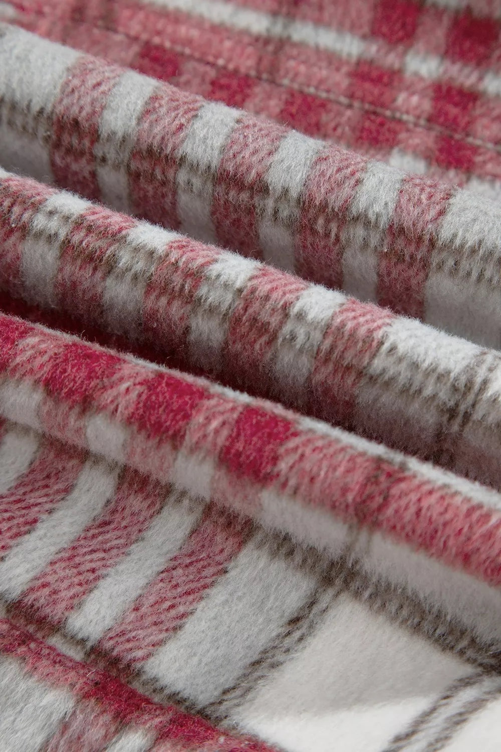 Close-up of soft pink, red, white, and gray plaid flannel fabric from a vintage shift jacket, showing its textured woven construction.