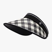 A black-and-cream plaid sun visor features a broad gently curved brim, woven upper, structured silhouette, contrasting black trim, and adjustable back fastening.
