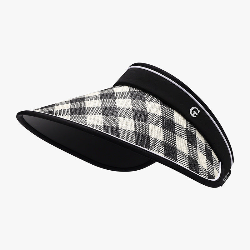 A black-and-cream plaid sun visor features a broad gently curved brim, woven upper, structured silhouette, contrasting black trim, and adjustable back fastening.