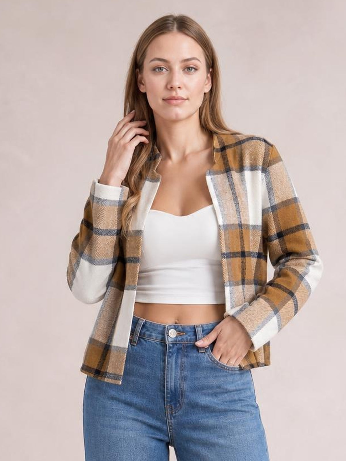 Model wearing a tan, white, and gray plaid open-front long sleeve jacket with a relaxed silhouette, posed with one hand in her jeans pocket.