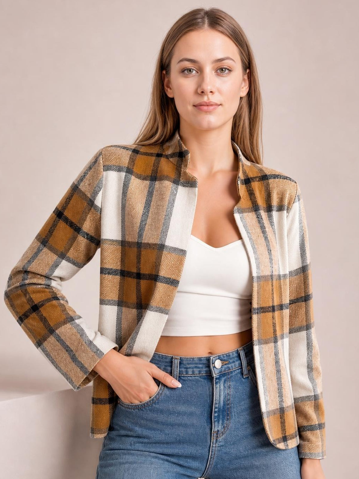 Model wearing a tan, cream, and black plaid open-front long sleeve jacket with a tailored silhouette, layered over a white top and jeans.