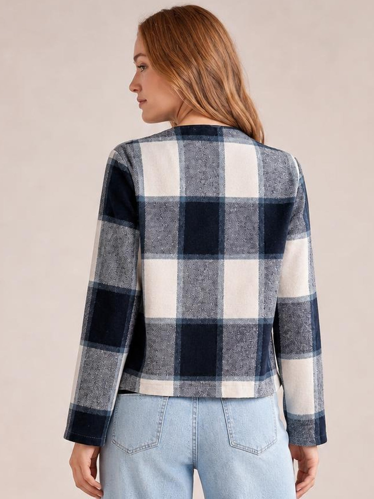 A model faces away wearing a navy, gray, and cream plaid open-front long-sleeve jacket with a straight, waist-length silhouette.