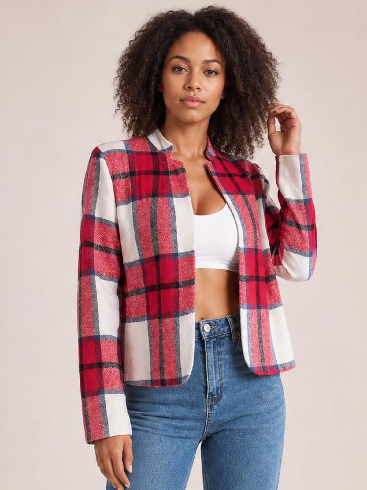 A model poses in a red, white, and navy plaid open-front long sleeve jacket with a structured silhouette, holding one hand near her hair.
