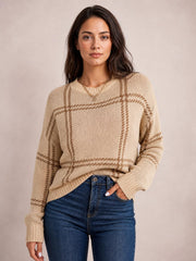 A model poses in a beige and brown plaid round-neck sweater with dropped shoulders, a relaxed silhouette, and ribbed cuffs and hem.
