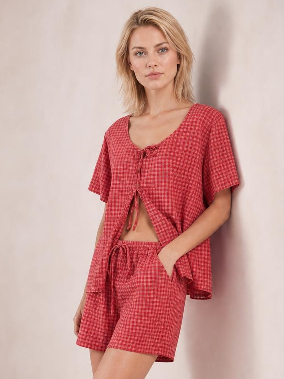 Model poses in a red plaid tied scoop-neck short-sleeve top with a relaxed cropped silhouette and matching drawstring shorts.