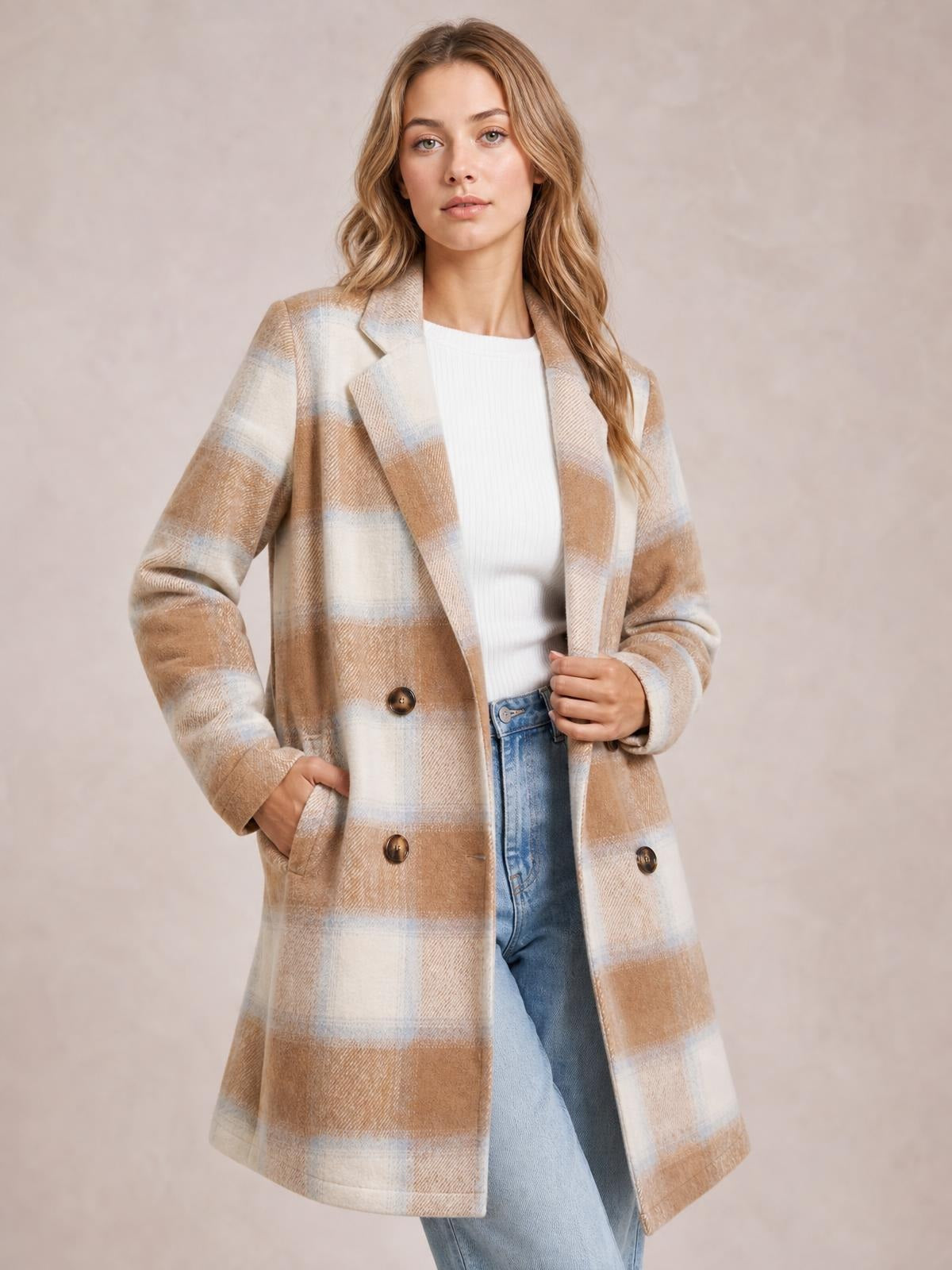 A model poses in a beige and cream plaid longline jacket with notched lapels, button closure, long sleeves, and front pockets.