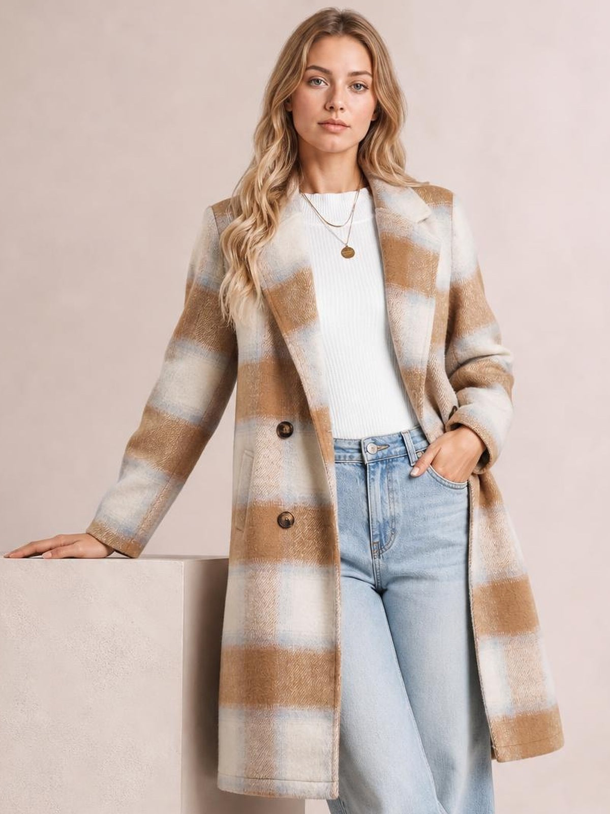 Model wears a beige, cream, and brown plaid wool blend longline jacket with a relaxed silhouette, notched collar, button front, and pockets.