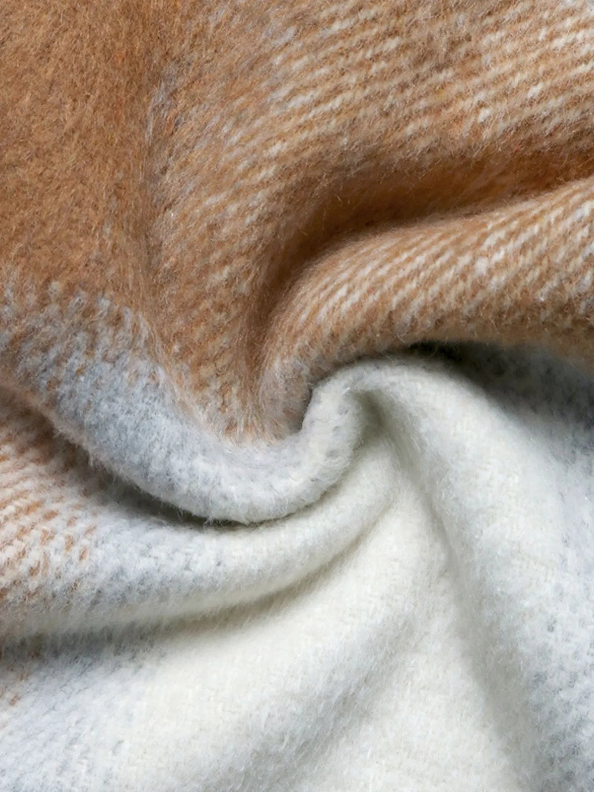 Close-up of the brown and cream brushed textile on a plaid longline jacket, showing its soft fuzzy surface and woven construction.