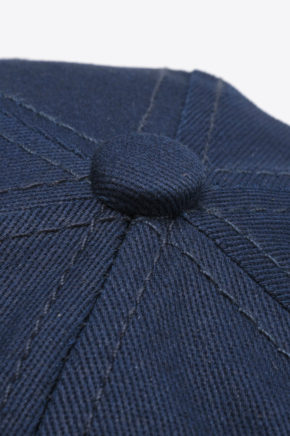 Close-up of a dark navy cotton baseball cap showing stitched panel seams and a covered top button in a solid, structured design.