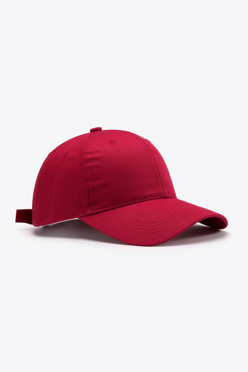 Red plain adjustable cotton baseball cap with a structured six-panel-inspired crown, gently curved brim, tonal stitching, and ventilation eyelets.