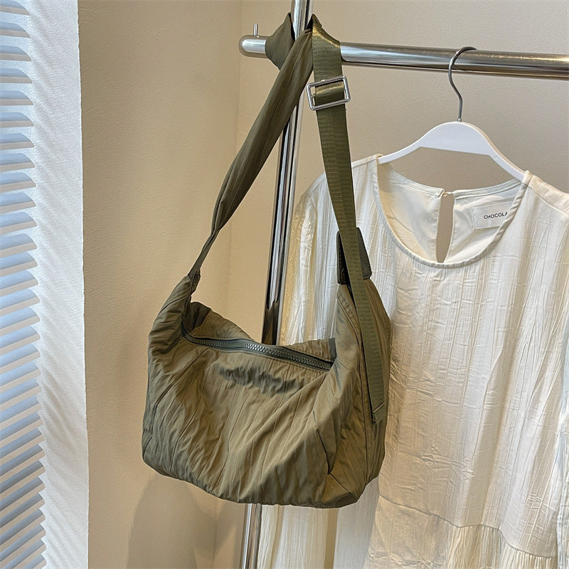 Olive green Pleated Dumpling crossbody bag with a softly slouchy crescent silhouette, gathered pleats, zip top, and broad adjustable shoulder strap.