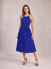 Model poses in a vivid blue pleated spaghetti strap midi dress with a defined tie waist and flowing A-line silhouette.