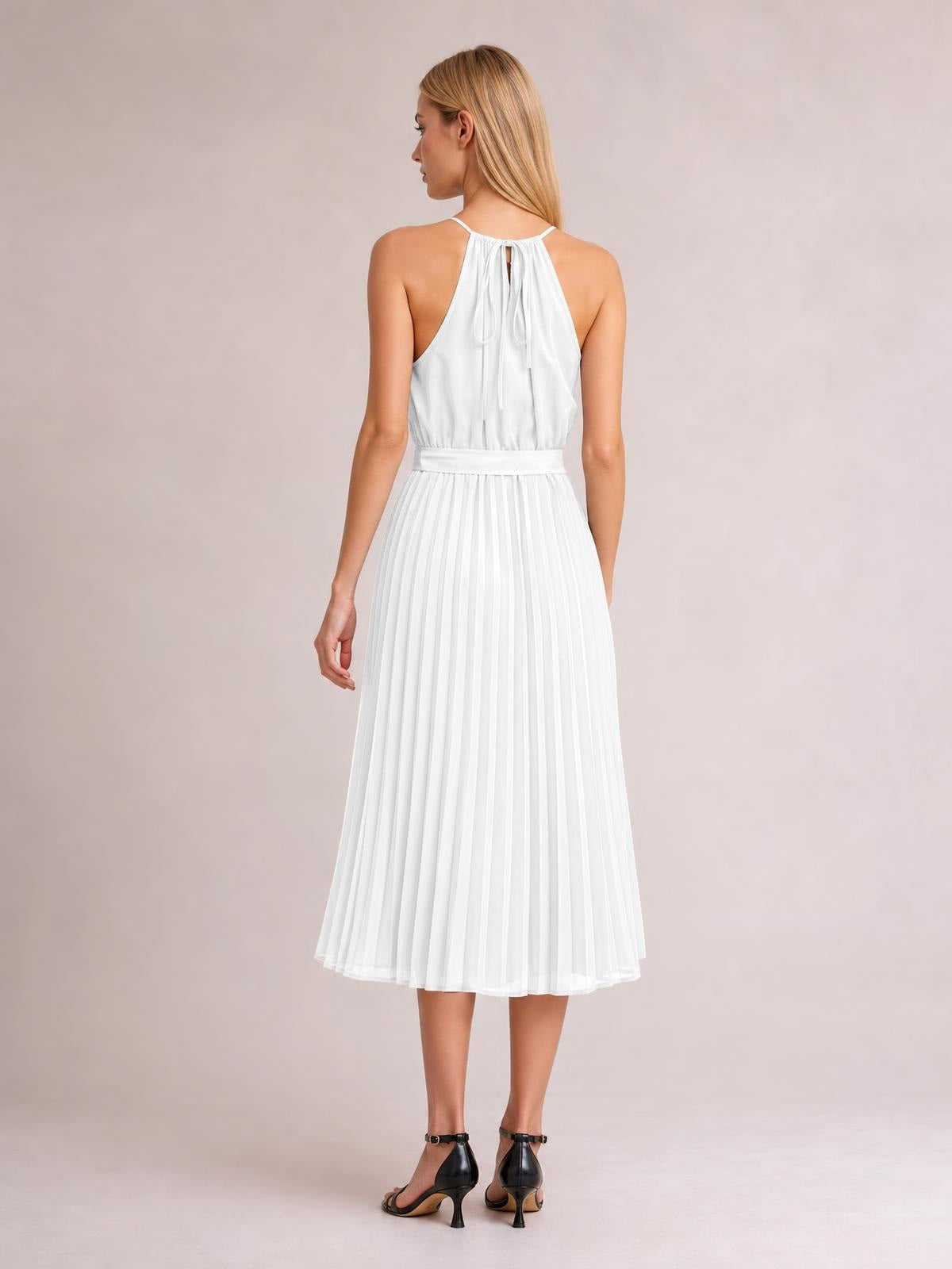 A model faces away in a white pleated spaghetti strap midi dress with a tied halter back, defined waist, and softly flared A-line silhouette.