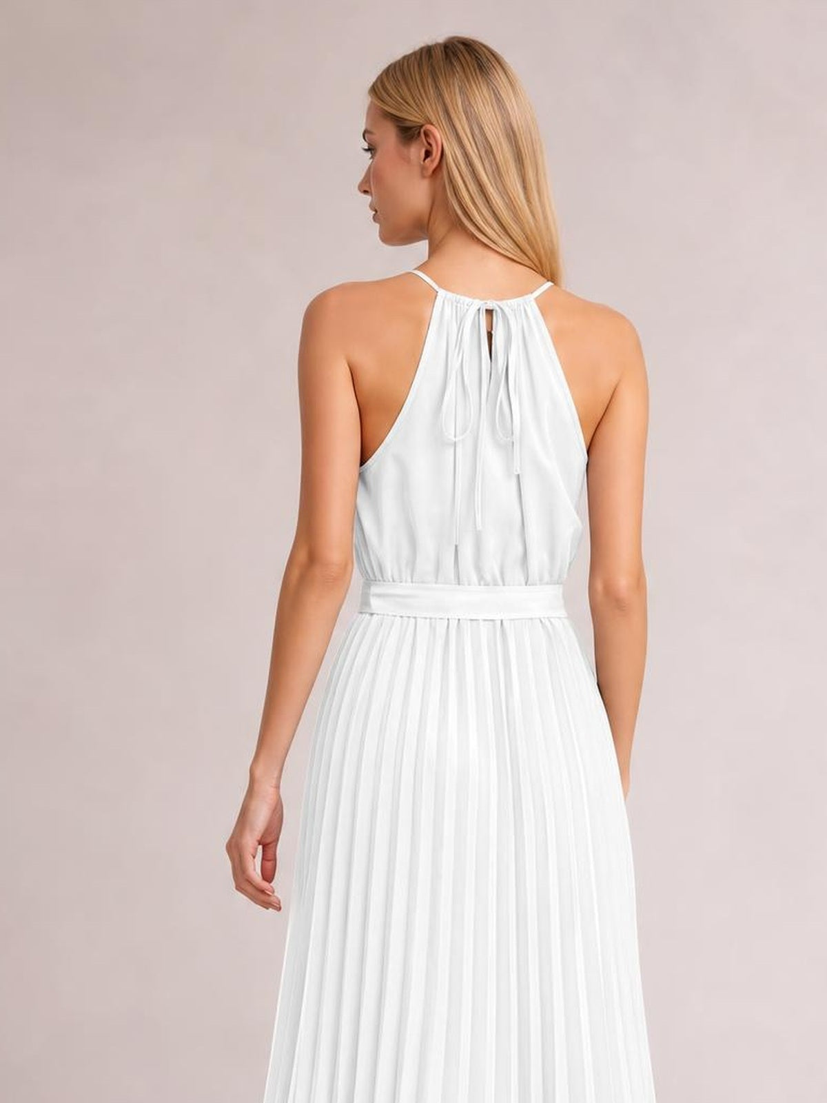 Model viewed from behind wearing a white pleated spaghetti strap midi dress with a tied halter neckline, defined waist, and flowing A-line silhouette.