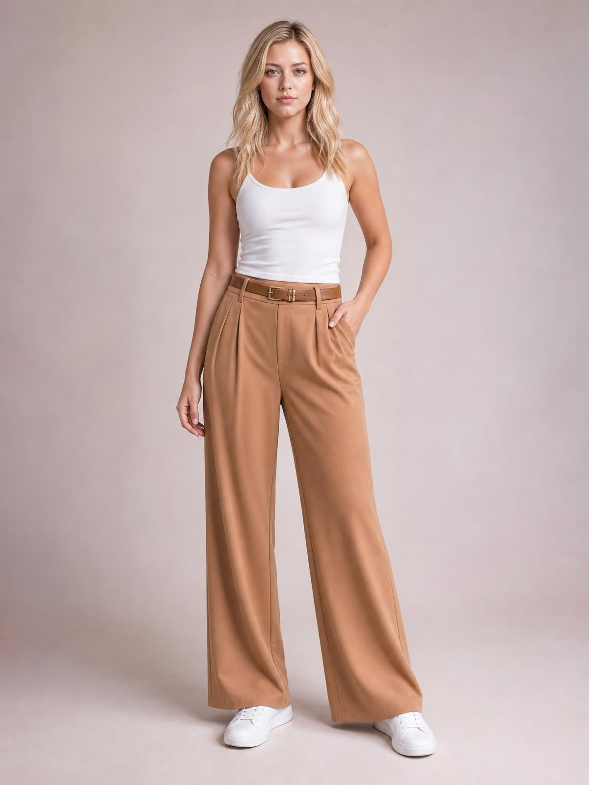 Model wearing camel pleated wide leg pants with a high waist, belt loops, front pleats, side pockets, and a flowing full-length silhouette.