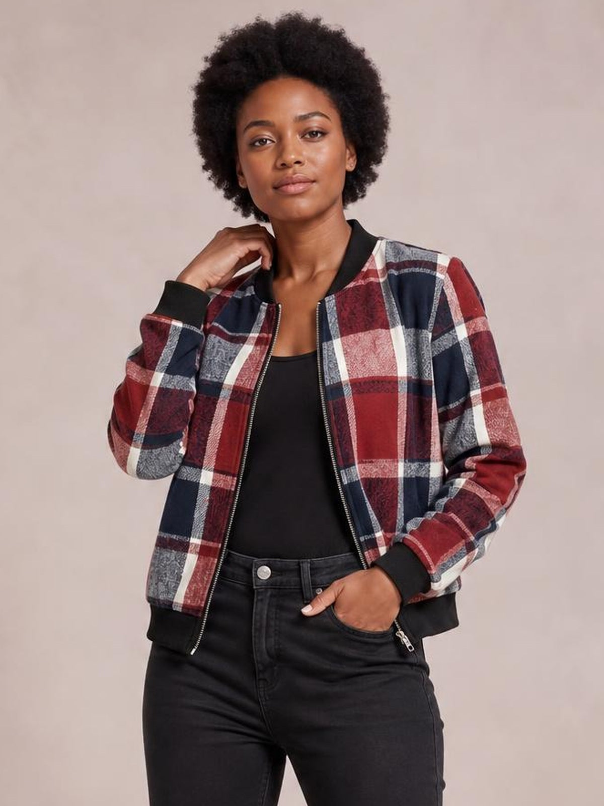 Model poses in a red, navy, and white plaid baseball collar zip-up jacket with ribbed black trim, long sleeves, and a relaxed cropped silhouette.