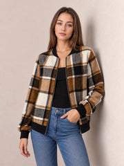Model wears a brown, black, cream, and gray plaid baseball collar zip-up jacket with ribbed cuffs and hem, posed with one hand in her jeans pocket.