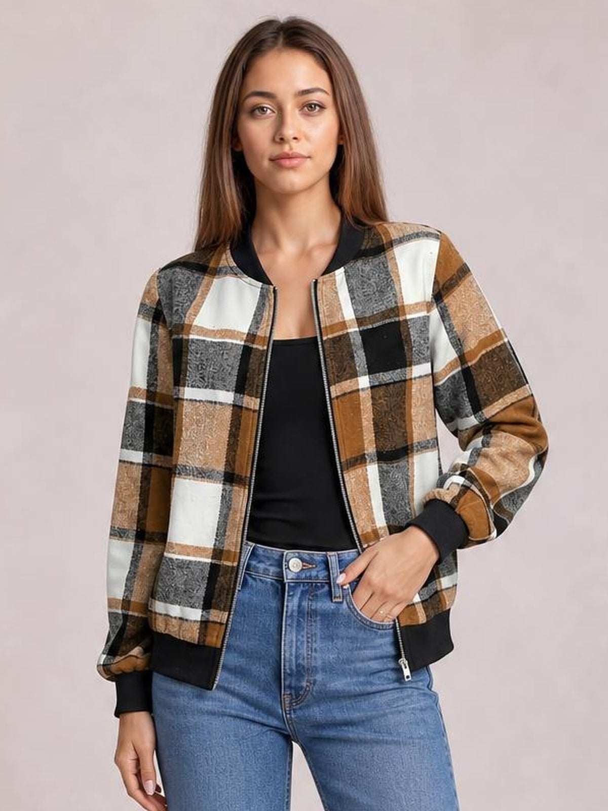 Model wearing a brown, black, white, and gray plaid baseball collar zip-up jacket with a relaxed silhouette, ribbed cuffs, and one hand in her jeans pocket.