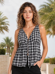 A model stands with one hand in her pocket wearing a black-and-white plaid halter neck cami with a sweetheart neckline, tie detail, gathered waist, and flared silhouette.