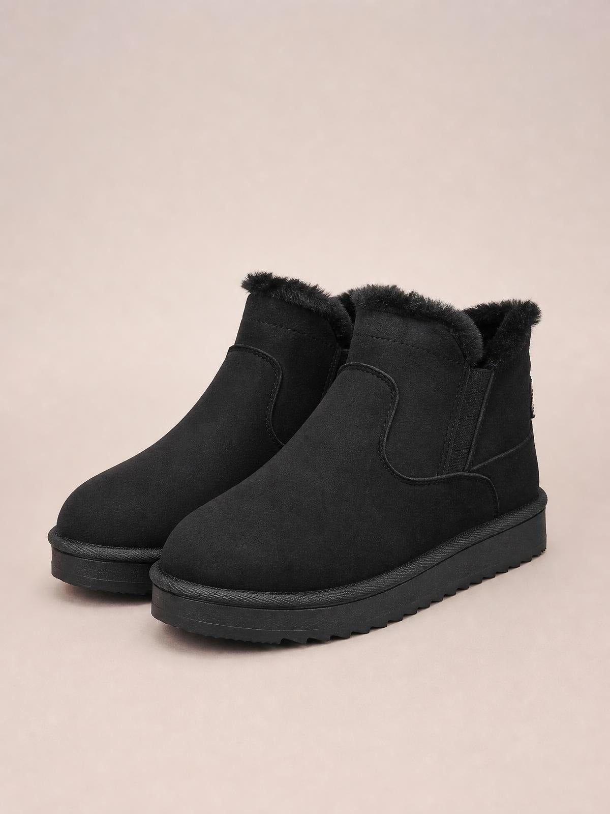 Black plush-lined winter ankle boots feature a rounded silhouette, soft suede uppers, fluffy cuffs, flat rubber soles, and stitched panel construction.