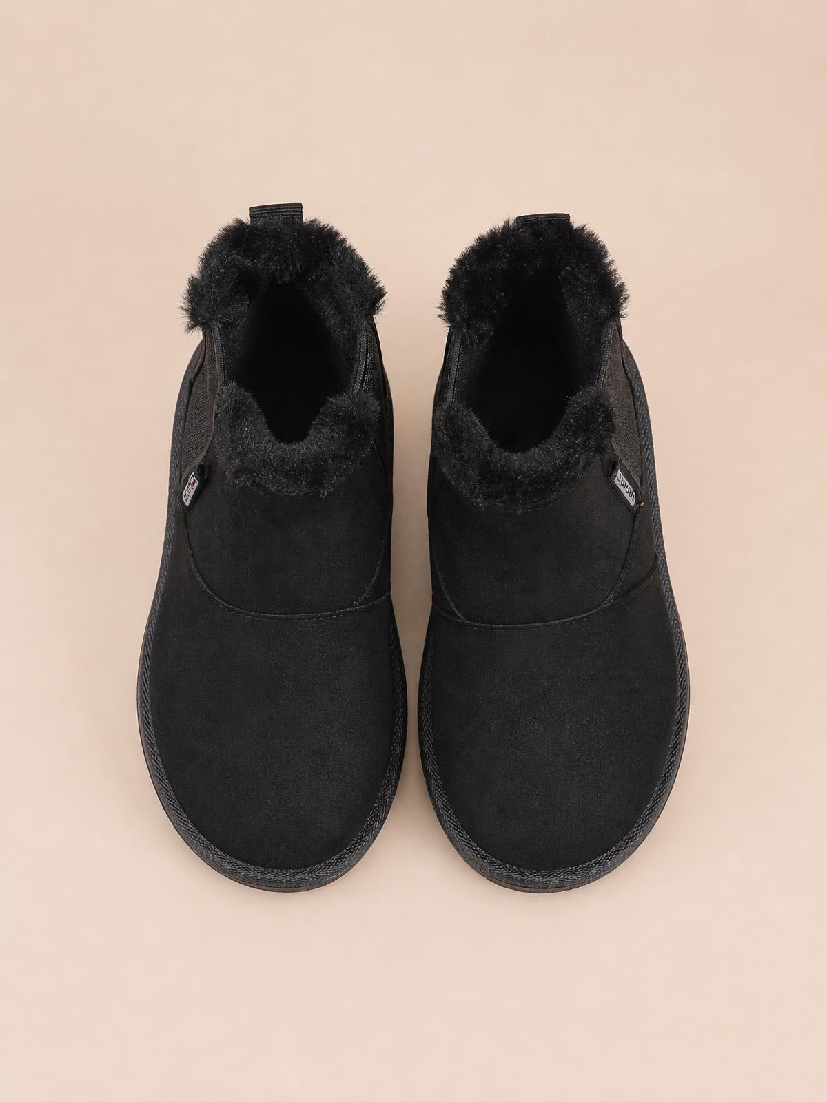 Pair of black plush-lined winter ankle boots with rounded toes, soft suede uppers, visible fluffy lining, flat rubber soles, and stitched panel construction.