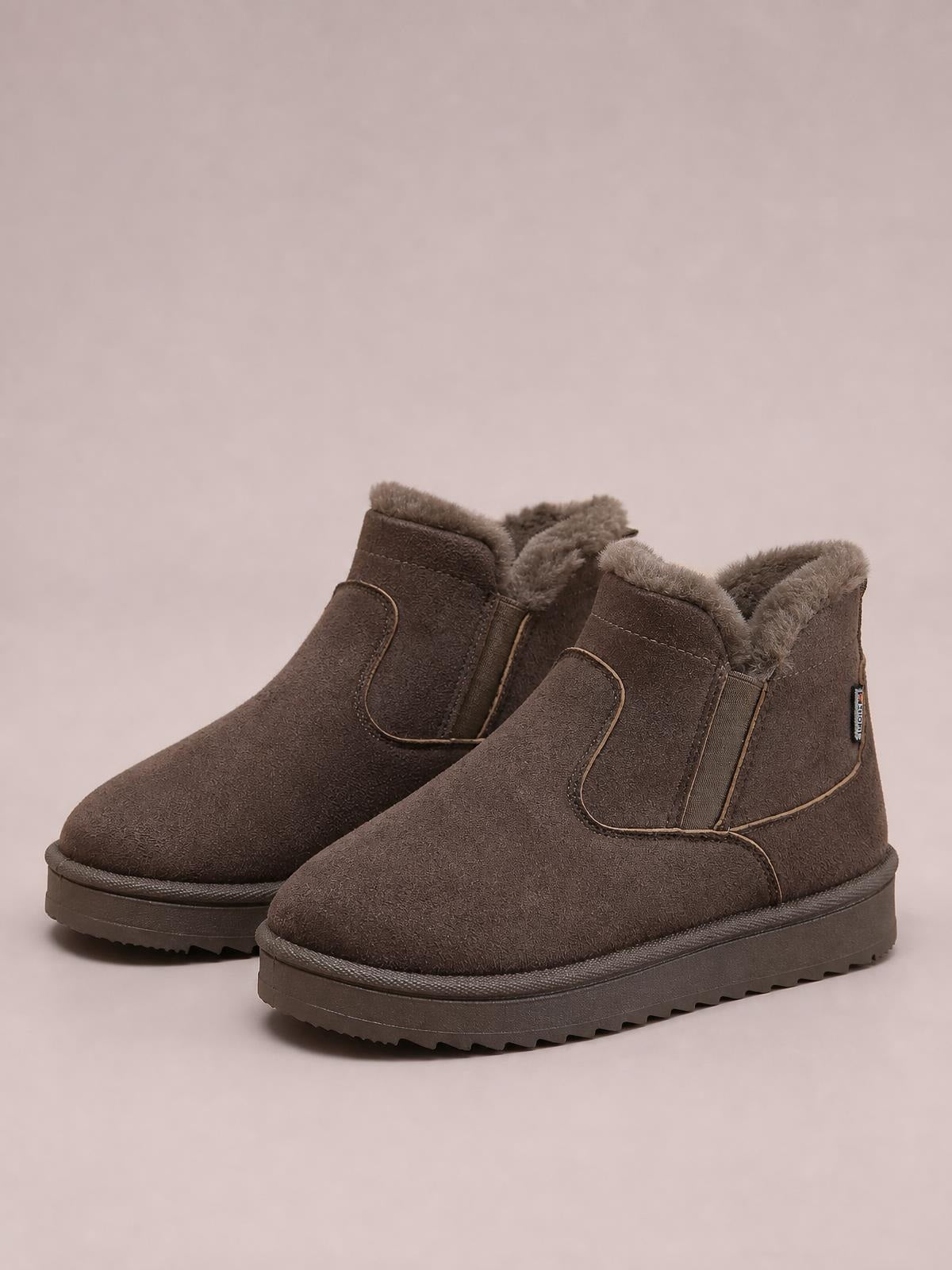 Brown suede winter ankle boots feature plush-lined collars, rounded toes, stitched panel construction, flat profiles, and sturdy lugged rubber soles.