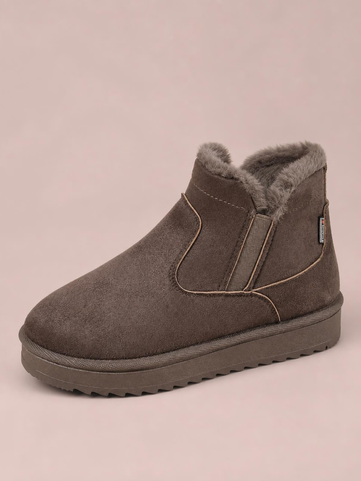 Brown suede winter ankle boot with plush lining, elastic side panels, stitched trim, rounded toe, flat rubber platform sole, and lugged tread.