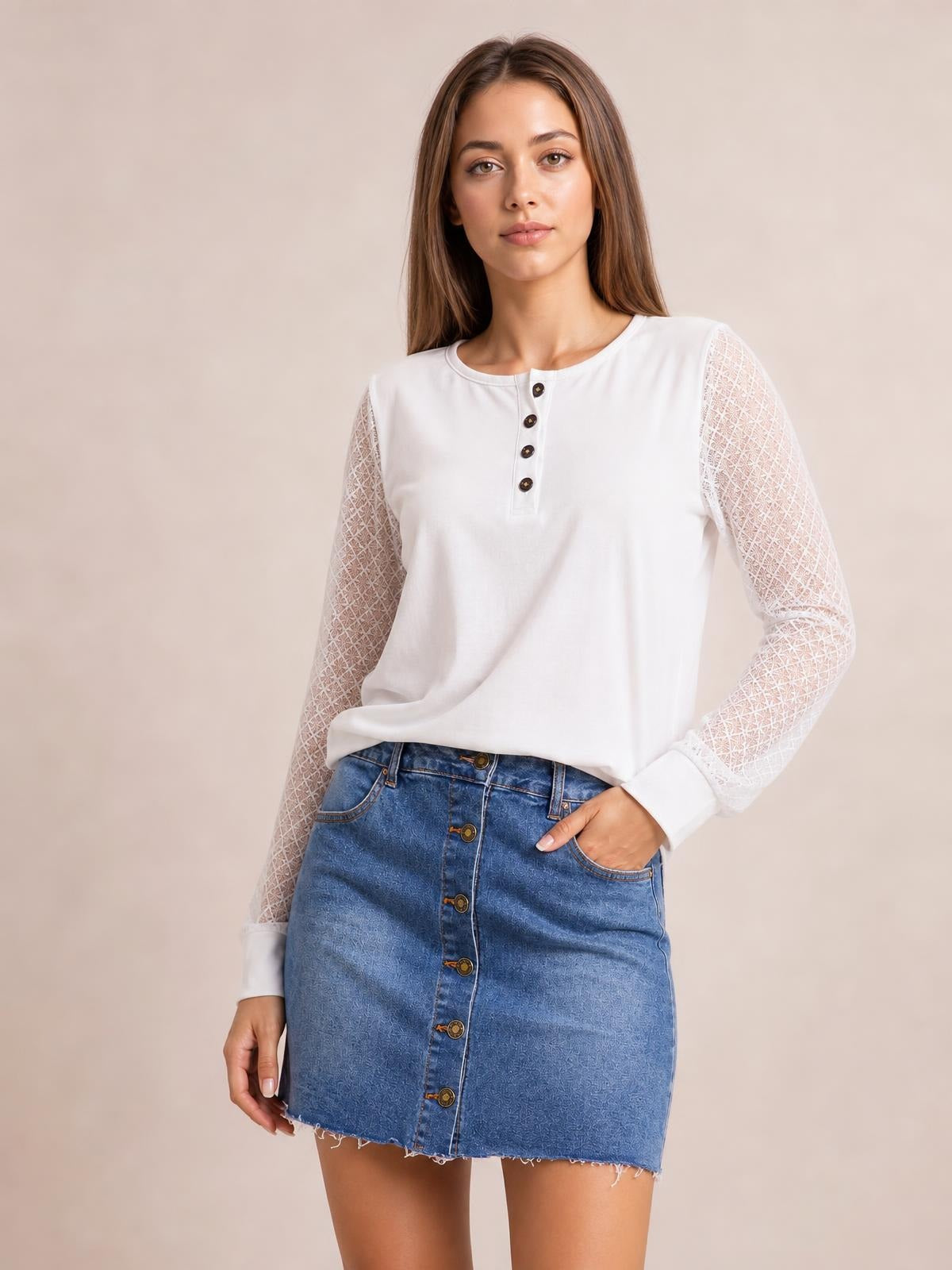 Model wears a blue denim mini skirt with a straight silhouette, front button closure, visible pockets, and a frayed raw hem, posing with one hand in a pocket.