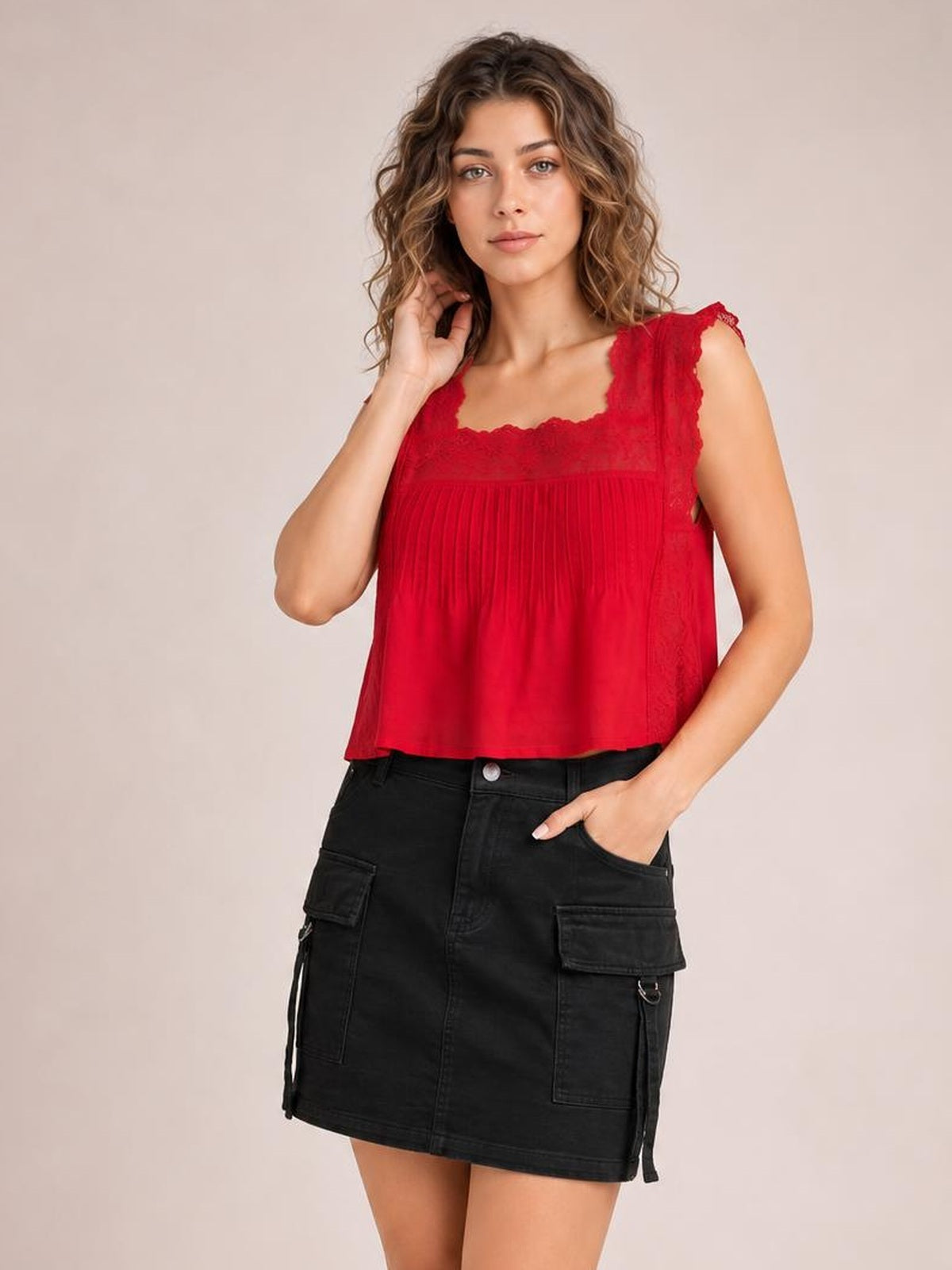 A model poses with one hand in the pocket, wearing a black denim mini skirt with a buttoned front, belt loops, and multiple practical patch pockets.