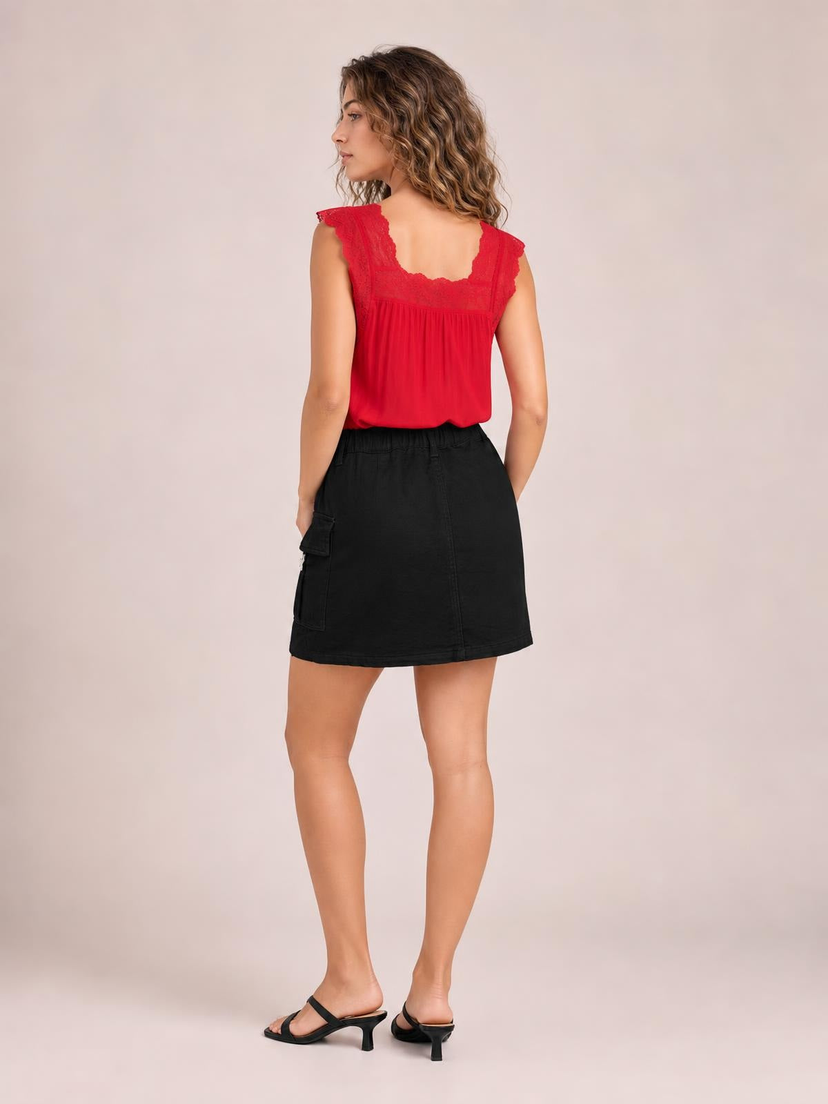 Model turned away wears a black denim skirt with a comfortable waistband, practical side pocket, straight mini silhouette, and neatly stitched hem.