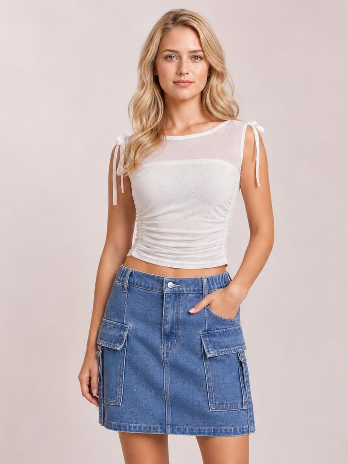 A model poses in a blue denim skirt with a straight mini silhouette, front button closure, contrast stitching, and multiple practical patch pockets.